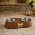 Maison quiet luxury brown quilted double pet feeder bowl with gold bow detail on a marble counter.